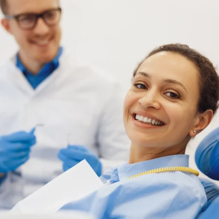 portrait-smiling-woman-posing-camera-dental-chair-with-male-dentist-background